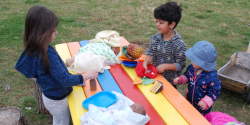 children at an outdoor table with toys